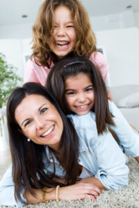 Portrait of beautiful mother with her daughters looking at camera at home.